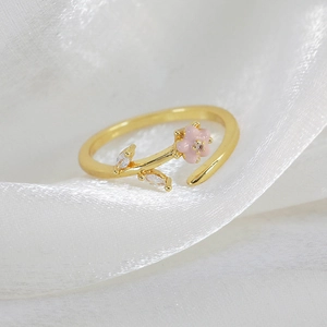 Detailed macro view of gold-plated flower ring with pink enamel and marquise crystals