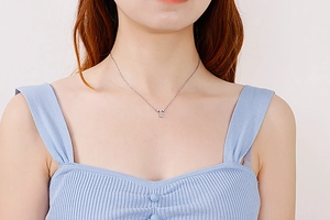 Detail shot of a silver letter T pendant necklace with sparkling rhinestones on a model
