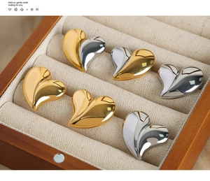 Détail de boucles d'oreilles cœur en métal doré et argenté dans une boîte en bois