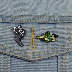 Gothic skull lady and green water monster enamel pins on blue denim jacket pocket
