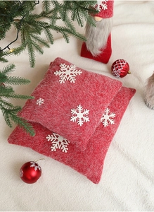 Close-up of red Christmas pillow with white snowflake embroidery on plush fabric