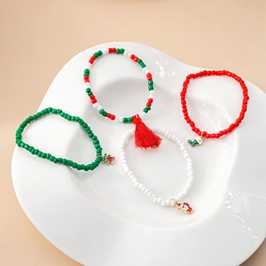 Detail of four Christmas beaded bracelets with festive charms on a decorative white tray