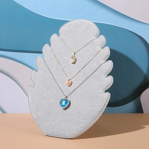 Grey velvet flame-shaped jewelry display stand showing multiple necklaces on a blue backdrop