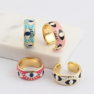 Detail of four gold-plated evil eye enamel rings on a white marble surface