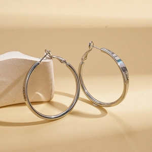 Macro detail of silver round hoop earring with engraved lettering on polished metal