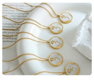 Macro detail of gold plated rose enamel pendants on a delicate chain in a French vintage style