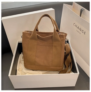 Brown canvas tote bag with adjustable strap and external pocket in a premium white gift box
