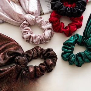 Close-up of metallic silk hair scrunchies with bunny ears in multiple festive colors
