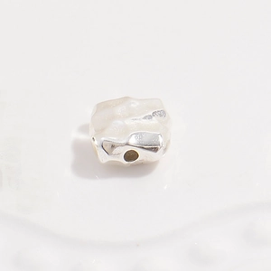 Macro view of a single S925 silver irregular hammered spacer bead for jewelry making