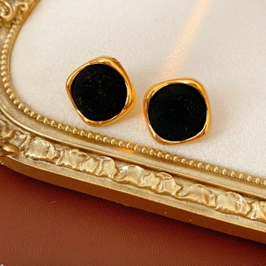Vue macro de boucles d'oreilles carrées dorées avec velours noir sur fond vintage