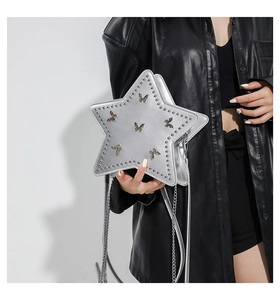Silver star-shaped handbag with butterfly motifs and metal studs held by model