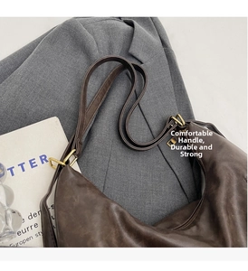 Detail of dark brown matte leather tote bag with vintage gold metal hardware on blazer