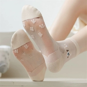 Detail of sheer glass silk socks featuring cute cartoon bear patterns on beige fabric