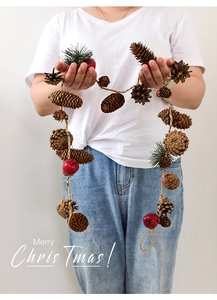 Detail of Christmas garland with natural pine cones, red berries, and pine needles on rope