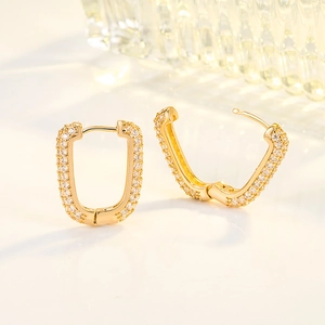 Eleganti orecchini geometrici a U dorati con cristalli pavé su sfondo minimalista