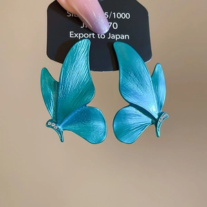 Macro shot of 925 silver butterfly earrings with teal finish and delicate pave diamonds