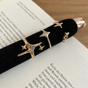 Golden star and cross zircon ring set for women on black velvet display with book