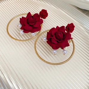 Detailed close-up of red fabric rose earrings with pearls and golden circular hoops