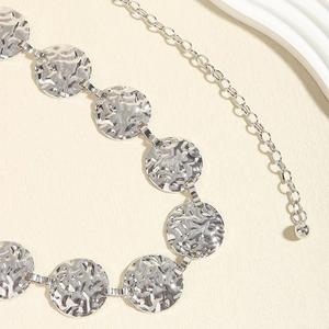 Close-up of silver metal chain belt with textured round discs and adjustable extension chain