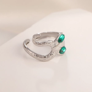 Macro shot of snake scale textured stainless steel ring with two green faceted gemstones