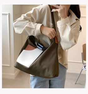 Detail of color-block canvas tote bag worn over the shoulder in military green and orange
