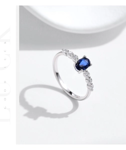 Makroaufnahme eines ovalen saphirblauen Edelsteinrings mit seitlichen Diamantakzenten