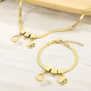 Detailansicht der goldenen Schlangenkette mit Herzanhängern und weißen Perlenakzenten