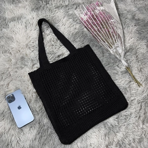 Detail showing the intricate crochet mesh texture and woven handle of the black knit tote bag