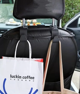 Detail view of black ABS car headrest hooks holding a shopping bag on the seat back