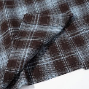 Close-up of flannel plaid fabric in brown and blue with high-quality stitching details