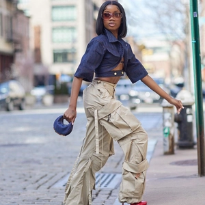 Detail of cropped dark blue denim jacket styled with khaki multi-pocket cargo pants