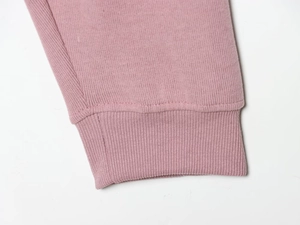 Gros plan détaillé des poignets côtelés élastiques et du tissu doux de ce sweat à capuche rose