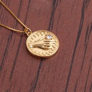 Vue détaillée du pendentif vintage doré avec paume gaufrée et cristal de zircone