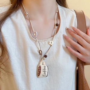 Detail of coffee cup pendant necklace with beads and heart charms on a model