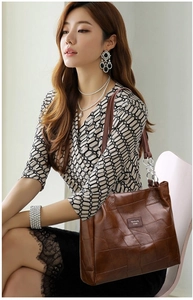 Close-up of brown PU leather tote bag with geometric stitching and chain handle detail