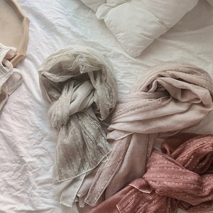 Linen cotton lace scarves in beige and pink tones laid on cozy white bedding