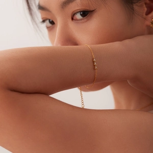 Détail d'un bracelet en acier doré orné de trois zircons blancs en forme de goutte d'eau