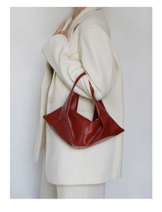 Burgundy oil wax leather croissant bag with geometric folding design on white blazer