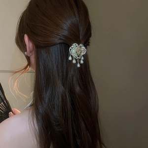 Detail view of a vintage Chinese style hair stick with green flowers and pearl tassels