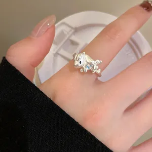 Macro détaillée d'une bague cheval en argent avec détails floraux bleus sur la main