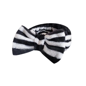 Elastic black and white striped coral fleece headband with a large plush bow decoration