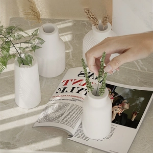 Detailed view of white minimalist resin vases with fine vertical ribbed texture on marble
