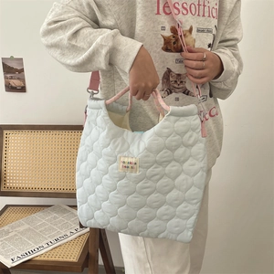 Détail du sac cabas matelassé bleu clair avec poignées en corde rose et patch coloré