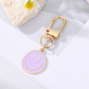 Detailed macro of gold plated alloy purple enamel smiley face pendant keychain accessory