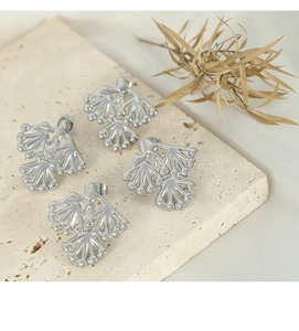 Macro detail of silver branch stud earrings with ball accents on natural stone base