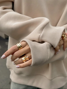 Close-up of minimalist gold rings on a knit sweater showing metallic texture
