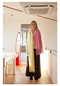 Detail of pink and yellow gradient wool scarf with long tassels on a female model