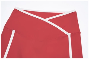 Detail of red yoga leggings featuring a V-shaped crossover waist and white piping