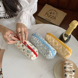 Fresh floral quilted makeup bags and stationery pouches displayed on a marble cafe table