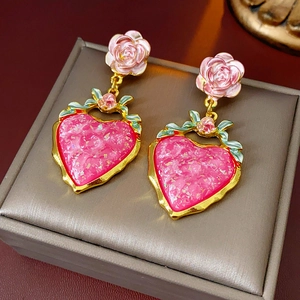 Macro shot of vintage style pink resin heart earrings with rose and leaf detail